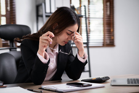 Business woman are stressed while working on laptop, Tired asian businesswoman with headache at office, feeling sick at work.の写真素材