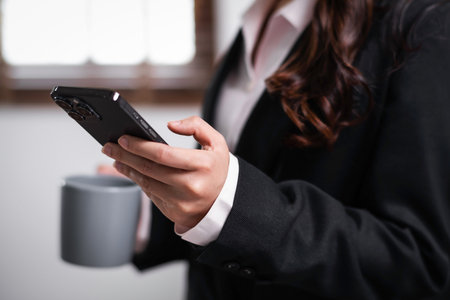 Close up of young asian confident businesswoman hand using smart phone mobile at office table working.の写真素材