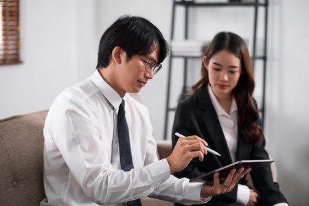 Young confident business people sitting at the office table working analyze on tablet and laptop computer with partner. Business concept.の写真素材