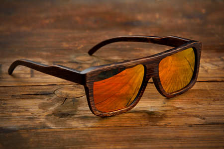 Dark brown wooden sunglasses on a wooden surfaceの写真素材
