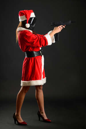 Sexy young girl in santa claus costume posing like playing paintballの写真素材