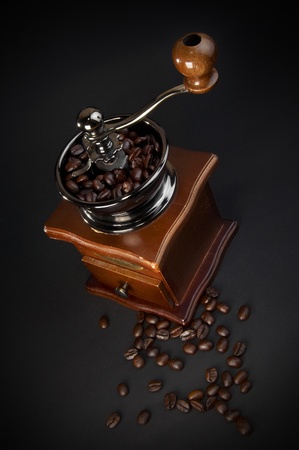 Old coffee grinder with beans on black backgroundの写真素材