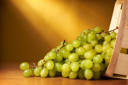 Green grapes in the basket on yellow backgroundの写真素材