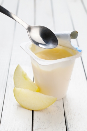 Yogurt and a slices of apple on a white wooden tableの写真素材