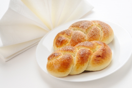 Two twisted buns on a white plate with a textile napkinの写真素材