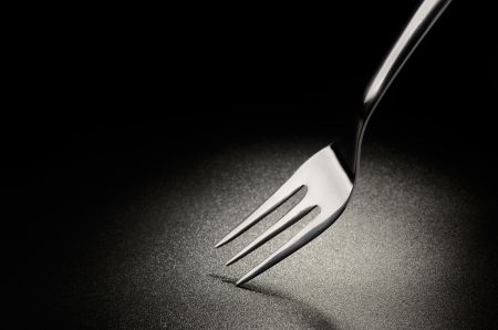 Cake fork on the black grained surfaceの写真素材