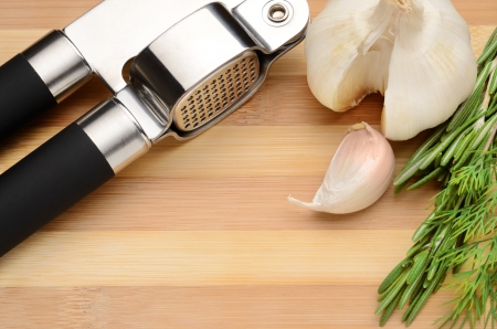 Garlic and spices with garlic press on the chopping boardの写真素材
