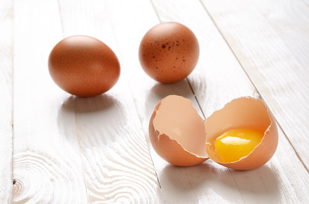 Broken egg on white wooden plank table