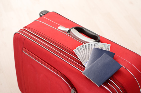 Red Suitcase, passports and money on a wooden floor in empty roomの写真素材