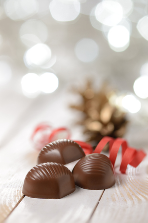 Delicious chocolate pralines on wooden table with blurred lightsの写真素材