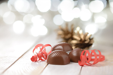 Delicious chocolate pralines on wooden table with blurred lights