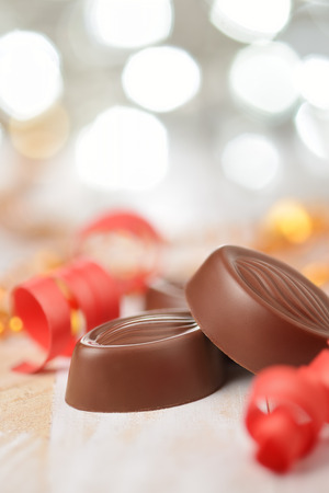 Delicious chocolate pralines on wooden table with blurred lightsの写真素材