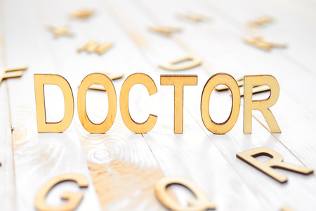 Word doctor made with wooden letters on the white plank tableの写真素材