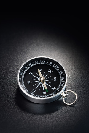 Metal modern compass on black plastic grained backgroundの写真素材