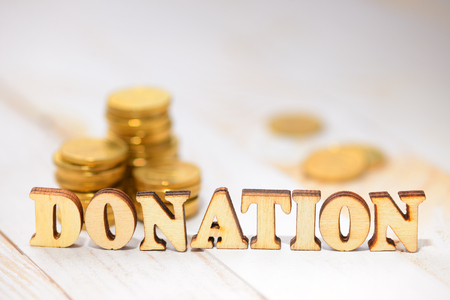 Word donation made with wooden letters and coins on the white plank tableの写真素材