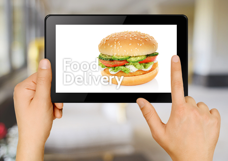 Hands with tablet ordering hamburger online. Food delivery conceptの写真素材