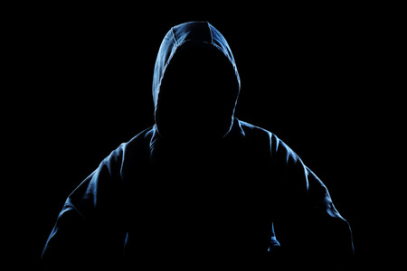 Silhouette of unrecognizable man in hoodie on black. anonymous or criminal conceptの写真素材