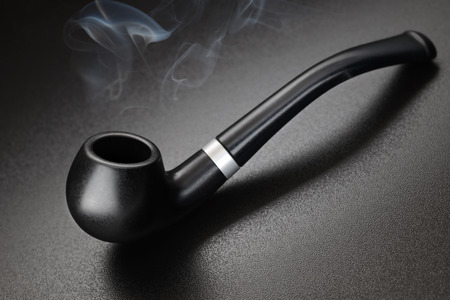 Black old fashioned smoking tobacco pipe on dark background