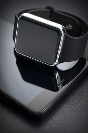Smart wrist watches and smartphone on black background. Devices connection conceptの写真素材
