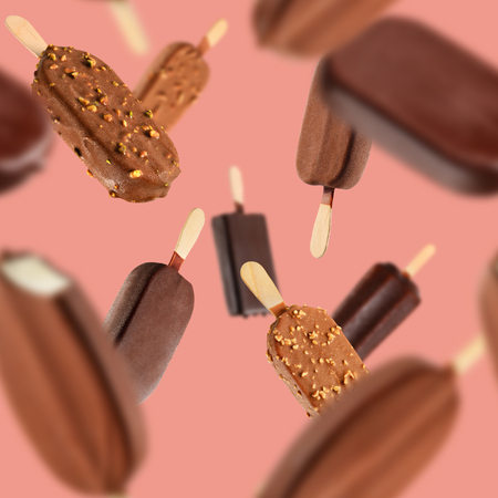 Falling chocolate ice creams on coral color background. Seamless texture or patternの写真素材