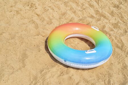 Multicolored swim tube or rubber ring on the yellow sandの写真素材
