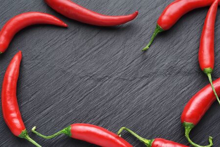 Frame with red chili peppers on dark black slate background. Top Viewの写真素材