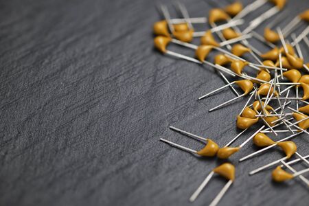 Heap of yellow multilayer ceramic capacitors MLCC on black slate surfaceの写真素材