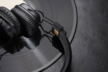 Over or on-ear headphones on vinyl record. Black background. Close-up shot