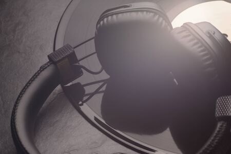 Over or on-ear headphones on vinyl record. Black background. Close-up shot