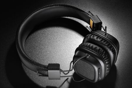Headphones. Wireless black on-ear earphones on dark slate backgroundの写真素材