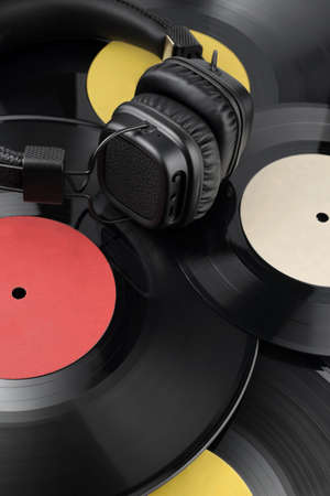 Headphones on the heap of different vinyl records with blank labels.