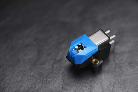 A magnetic phonograph cartridge on black slate background. Macro photo.