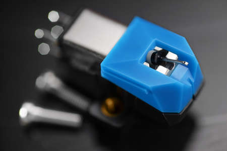 A magnetic phonograph moving coil cartridge on vinyl record. Macro photo.