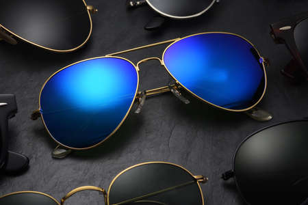 Set of different sunglasses arranged in a row on black slate backgroundの写真素材