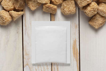 Blank white paper square sachet pack and sugar cubes on wood plank tabletop. 3D rendering and photo mock-up template.の写真素材