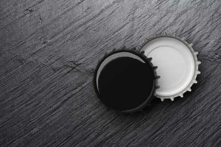 Black beer caps on dark slate background or texture. Mock up design template. 3D rendering illustration.の写真素材