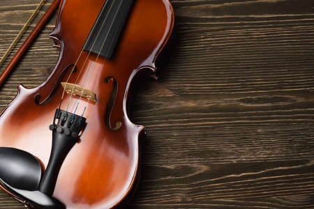 Violin with bow on brown wooden table with copy space, top view.の写真素材