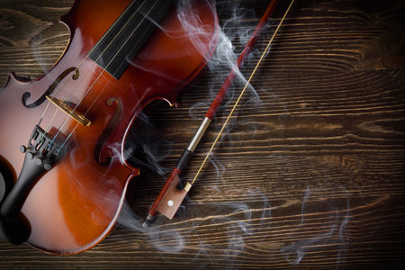 Violin with bow on brown wooden table with copy space, top view.の写真素材