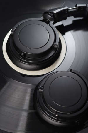 Vinyl record with black headphones close-up macro shot. Old-fashioned music concept.