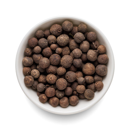 Dry allspice pepper in round bowl isolated on white background. Top view.