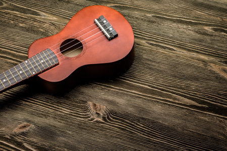 Hawaiian ukulele guitar on brown wooden background. Copy space. Top view.の写真素材