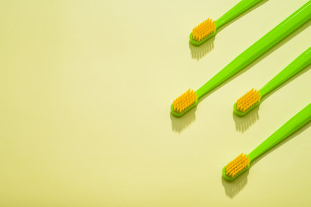 Modern green kids toothbrushes on a yellow background. Flat lay style, top view, Copy space for your text,の写真素材