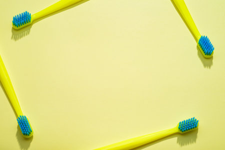 Modern yellow kids toothbrushes on a yellow background. Flat lay style, top view, arranged in a frame. Copy space for your text,の写真素材