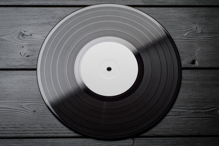 One EP vinyl record with blank label on black wooden background. Top view, flat lay.の写真素材