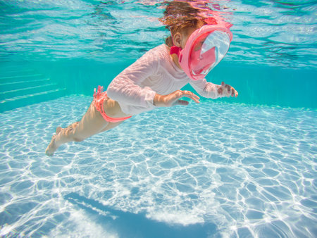 Little girl snorkeling underwater in the pool. Learning child to swim and diving. Kids water sports activity.の写真素材