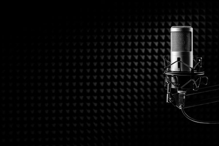 Professional microphone on the black acoustical wall panel background. Recording studio, copy space.の写真素材