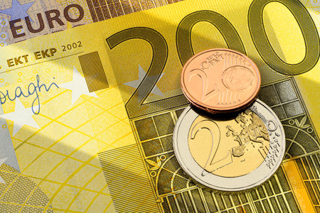 Different euro coins, one euro and one cent on the top of 200 yellow euro banknote.