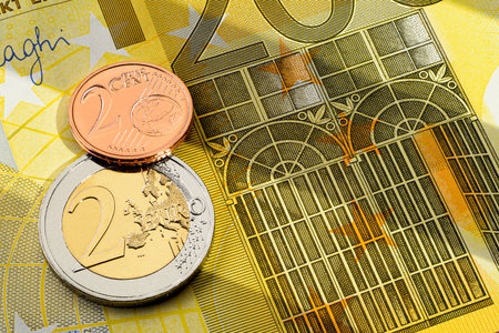 Two Euro coins, one 2-cent and one 2-euro, placed over a 200 yellow banknote.
