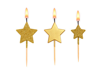 Golden decorated burning birthday candles shaped as star isolated on white background.の写真素材
