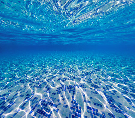 Swimming pool underwater, blue tiles with light rays caustic reflections.の写真素材